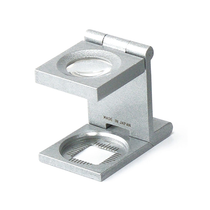 The classic Alfa Mirage folding loupe linen tester standing upright, showing its genuine Made in Japan engraving. The classic Alfa Mirage folding loupe linen tester standing upright, showing its genuine Made in Japan engraving.