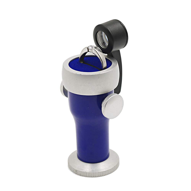 The blue JYBS diamond inscription viewer holding a silver engagement ring on its rotating cushioned platform stage. The blue JYBS diamond inscription viewer holding a silver engagement ring on its rotating cushioned platform stage.
