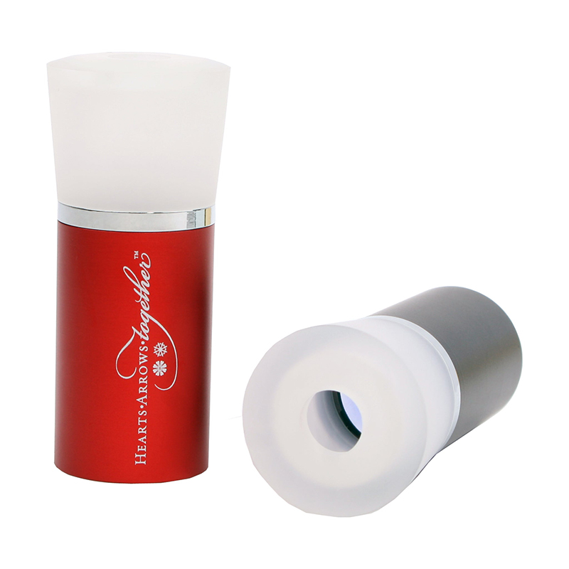 A red JYBS loupe highlighting the "Hearts • Arrows together" print layout shown beside a black barrel demonstrating the top view eyepiece aperture. A red JYBS loupe highlighting the "Hearts • Arrows together" print layout shown beside a black barrel demonstrating the top view eyepiece aperture.