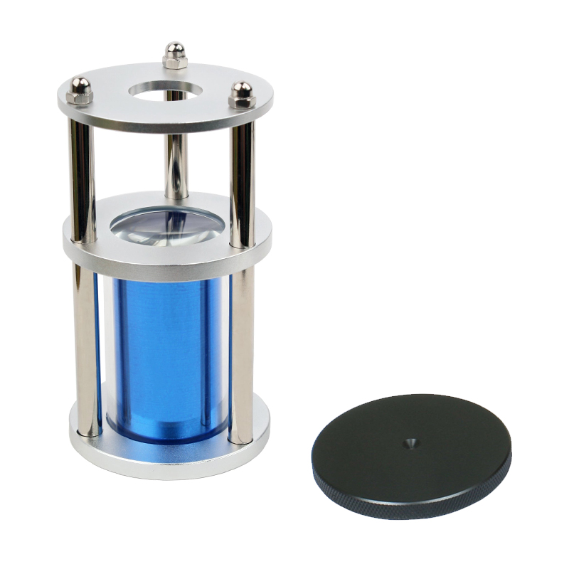 The blue metal JYBS 10X magnification optical column displayed next to its detached, non-reflective black gemstone base disk. The blue metal JYBS 10X magnification optical column displayed next to its detached, non-reflective black gemstone base disk.