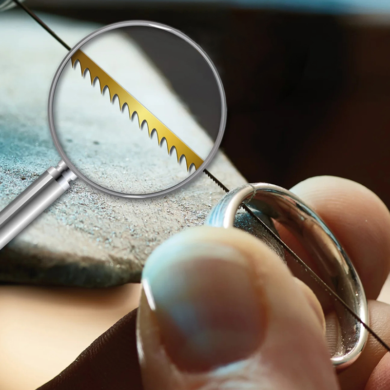 Magnified view of a NIQUA Super Q jeweler's saw blade cutting a silver ring; shows gold-colored, sharp teeth. Magnified view of a NIQUA Super Q jeweler's saw blade cutting a silver ring; shows gold-colored, sharp teeth.