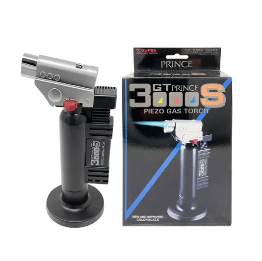 a product shot of a prince® gt 3000s piezo gas torch in black and silver with its base stand next to its black packaging