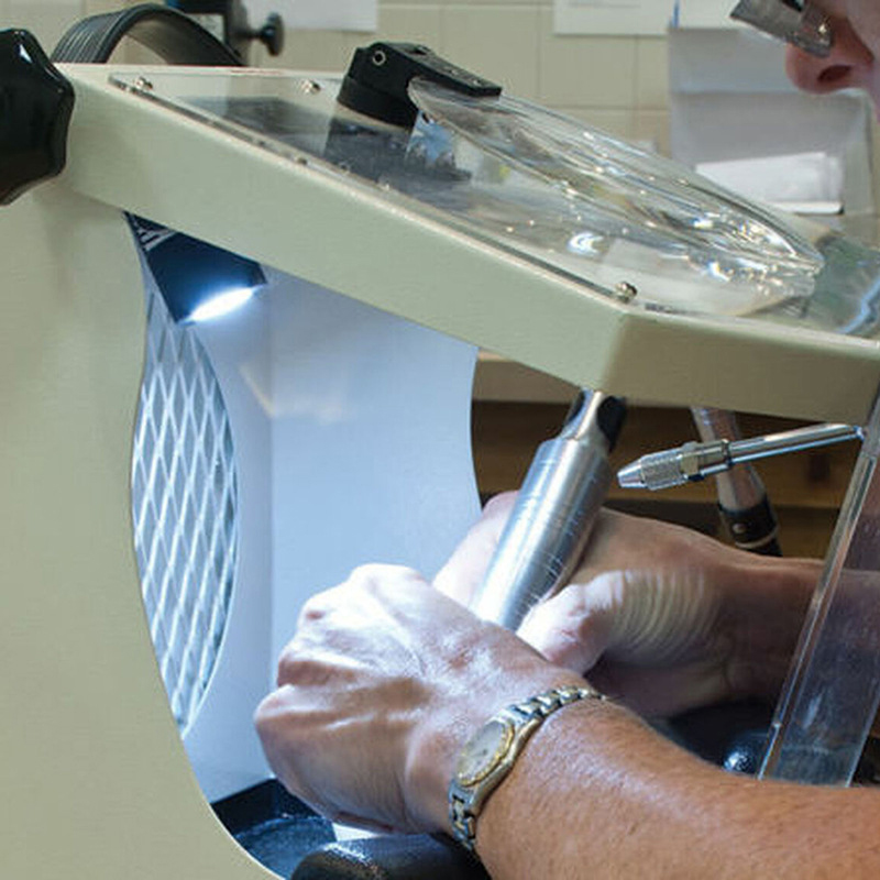Close-up of hands polishing inside the Foredom Work Chamber, showing the LED light and a rotary tool. Close-up of hands polishing inside the Foredom Work Chamber, showing the LED light and a rotary tool.