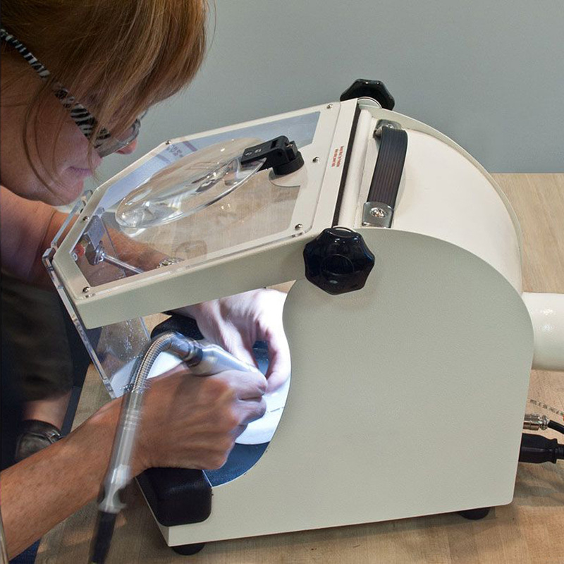Side view of Foredom MALC15 Work Chamber as a person uses a rotary tool inside for jewelry work. Side view of Foredom MALC15 Work Chamber as a person uses a rotary tool inside for jewelry work.