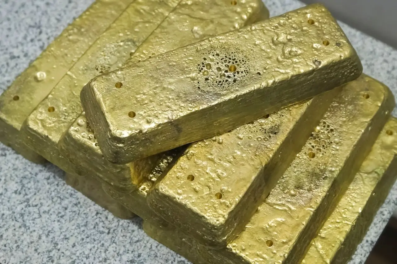A stack of rough unrefined gold bars with a textured surface resting on a light gray speckled counter.