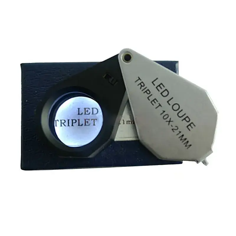LED triplet 10x 21mm jewelry loupe, magnifying "LED TRIPLET" text, on its blue storage box.