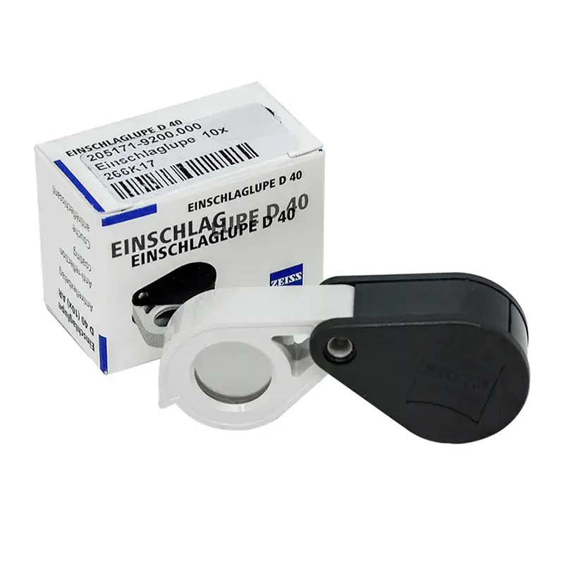 Zeiss Einschlaglupe D40 (10x magnification) folding magnifier and its branded retail box, isolated on white.