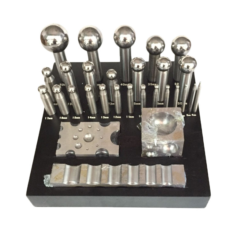 Steel dapping punches, forming blocks, and swage block organized on a labeled black wooden stand.