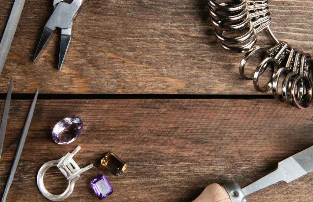 jewelry making tools and gemstones on a wooden workbench