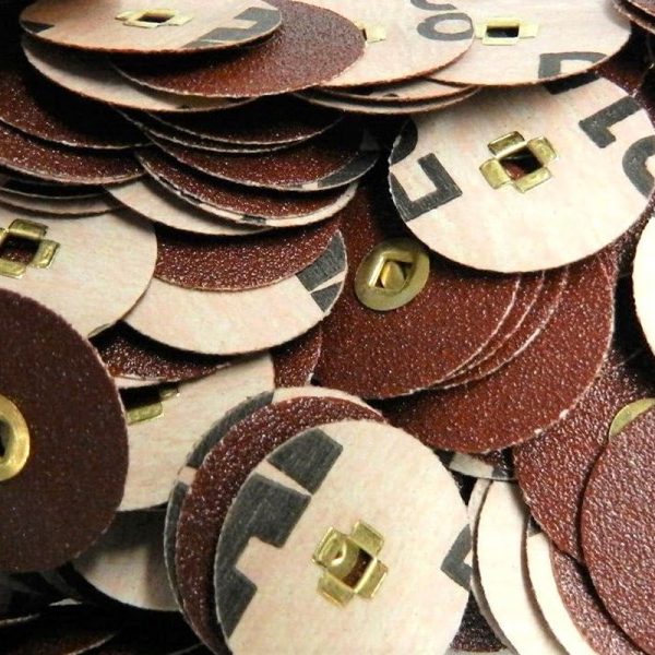 A close up pile of 22mm premium aluminum oxide sanding discs with brass centers