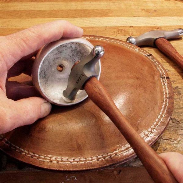 fretz large embossing hammer in use with hands working metal on a leather sandbag demonstrating embossing