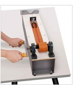 hands operating manual wire drawing bench on a table showing the hand crank in use scaled