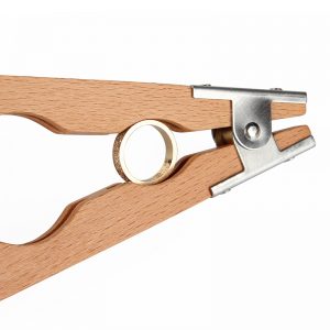 A Stuccler® wooden outside ring holder securely gripping a gold ring, showing the metal clamp mechanism