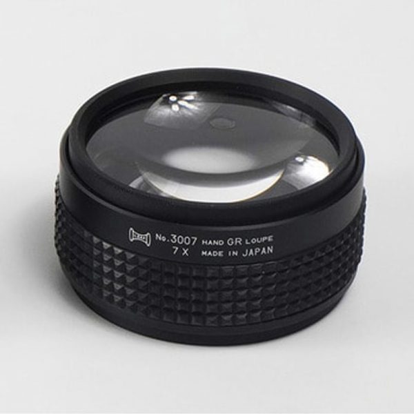 A close-up of a 7X magnification Hand Grip Loupe, showing the "7 X" and "MADE IN JAPAN" text on the side
