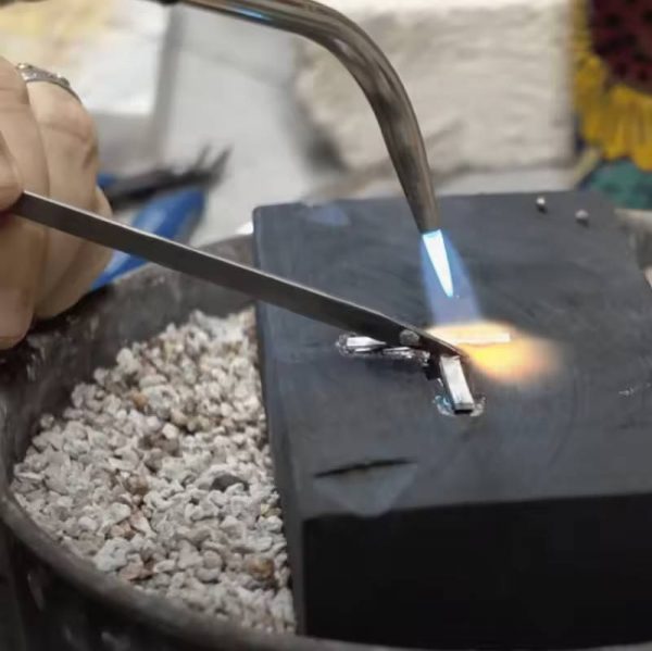 A close-up of the ErgoLast titanium soldering pick in use during jewelry welding, showcasing its non-stick properties