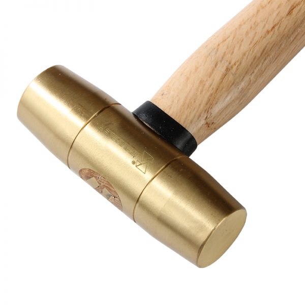 A close-up of the brass head of a Stuccler mallet, showing its texture and the logo stamp near the handle