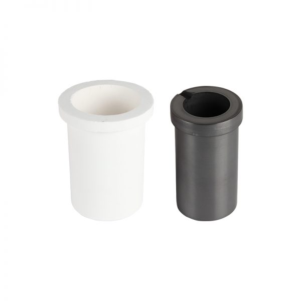 A close-up of two crucibles: a white ceramic and a black graphite one, used for melting different metals