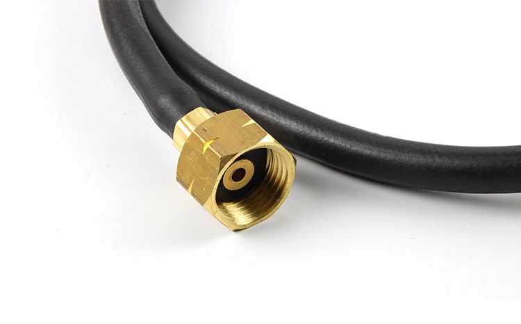 A close-up view of the brass fitting on the end of the gas hose, showing the threaded connection point and internal opening