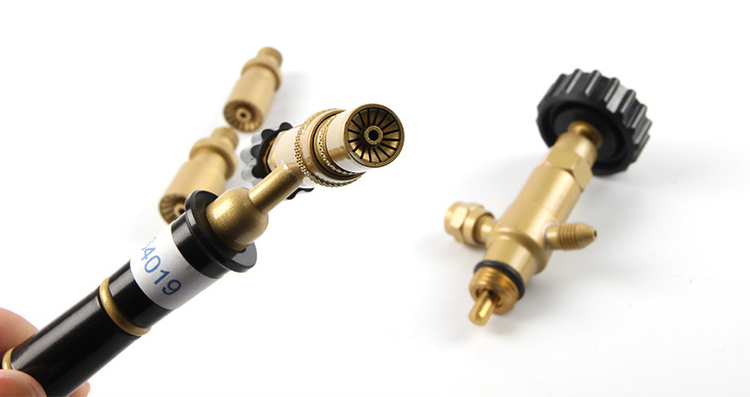 A hand holding the ORCA M75 CRD torch, showing its interchangeable nozzles and pressure regulator for jewelry soldering