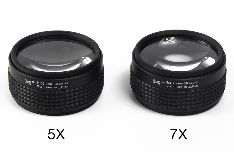 A side-by-side image of two black Hand Grip Loupes, one marked "5X" and the other "7X"