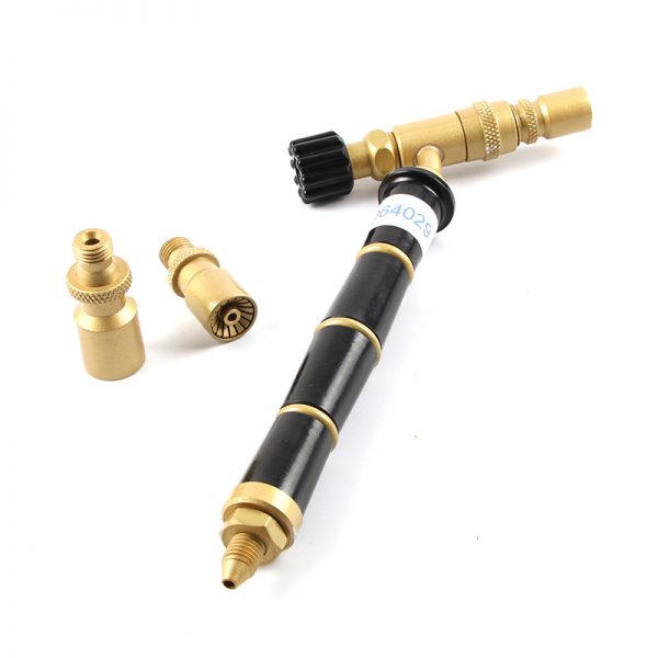 A brass and black ORCA M75 torch with a control knob and two different sized brass tips lying next to it