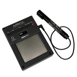 A close-up, angled view of the GEMORO AuRACLE Analyzer unit and its attached saline-based pen probe against a white background. The screen shows "Ready."