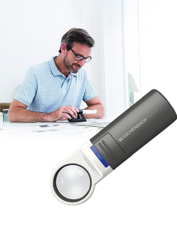 A person uses a black Eschenbach Mobilux LED magnifier to read documents, demonstrating its practical use.