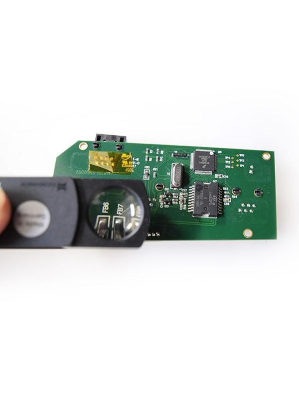 An Eschenbach 10x pocket magnifier being used to examine a detailed electronic circuit board.